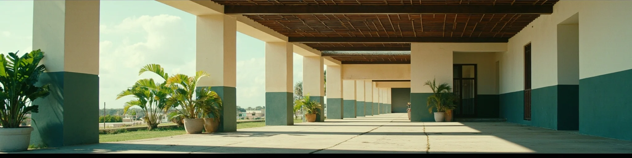 Corredor con columnas pintadas en blanco y verde y plantas